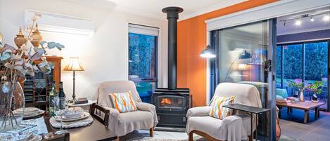 A cozy living room with two armchairs, a dining table, and a fireplace.