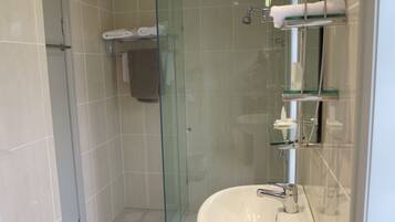 Un baño moderno con ducha de vidrio, lavabo blanco y barra para toallas.