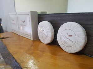 Trois paquets de savon blanc, avec des étiquettes, sont posés sur une étagère en bois.