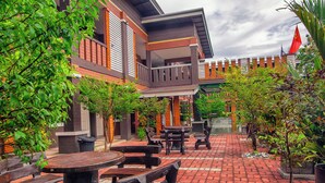 A courtyard with outdoor seating, potted plants, and a building with a balcony. - MyVilla Langkawi Hotel (Langkawi)