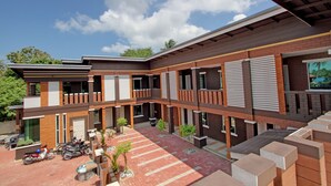 A modern multi-story building with a courtyard, featuring a mix of brick and wood paneling, and several balconies. - MyVilla Langkawi Hotel (Langkawi)