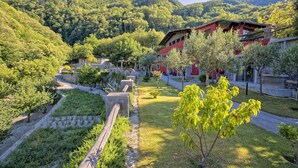 Ein traditionelles Gebäude mit rotem Dach, umgeben von einem gepflegten Garten und einem gepflasterten Weg.