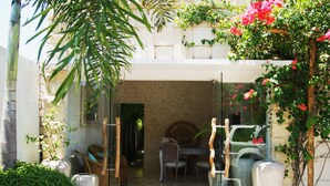 A courtyard with a dining area, large vases, and potted plants. - Harmony Villas Lombok (Kuta)