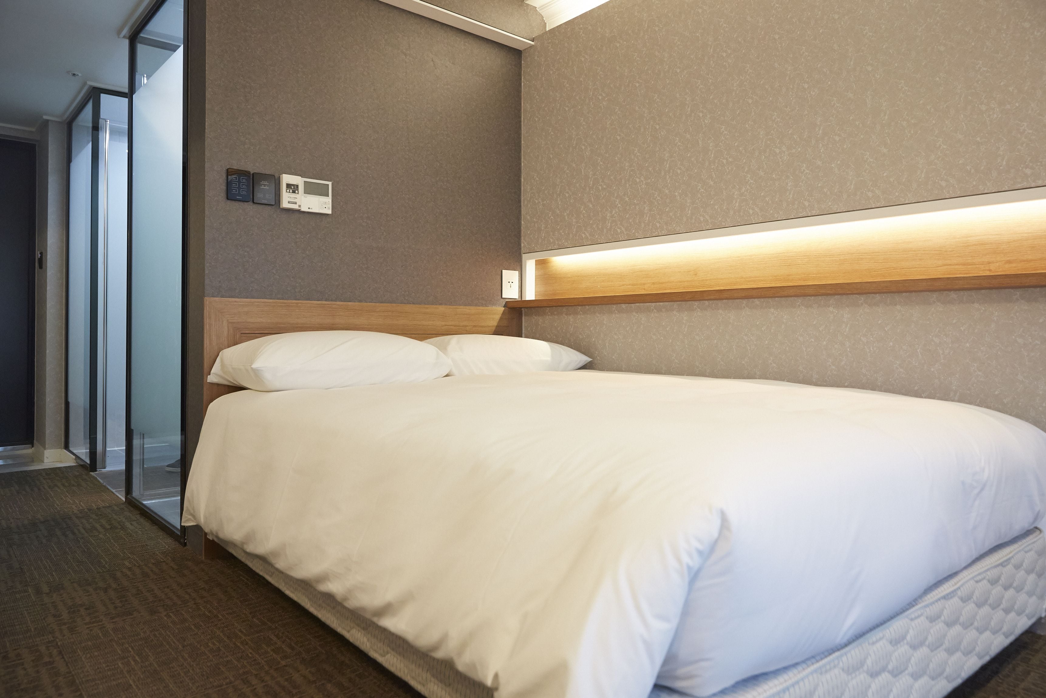 Een hotelkamer met een groot bed, een houten hoofdbord, een wandlamp en een glazen deur naar een balkon.