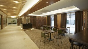 Un moderno vestíbulo de hotel con un mostrador de recepción alargado, varias zonas de estar y grandes ventanales con vistas.
