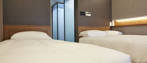 A hotel room with two beds, a modern design, and a built-in light fixture above the beds.