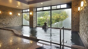 An indoor swimming pool with clear glass walls, a stone sculpture, and a tiled floor. - Seishounagon (Tsu)