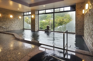 An indoor swimming pool with clear glass walls, a stone sculpture, and a tiled floor.