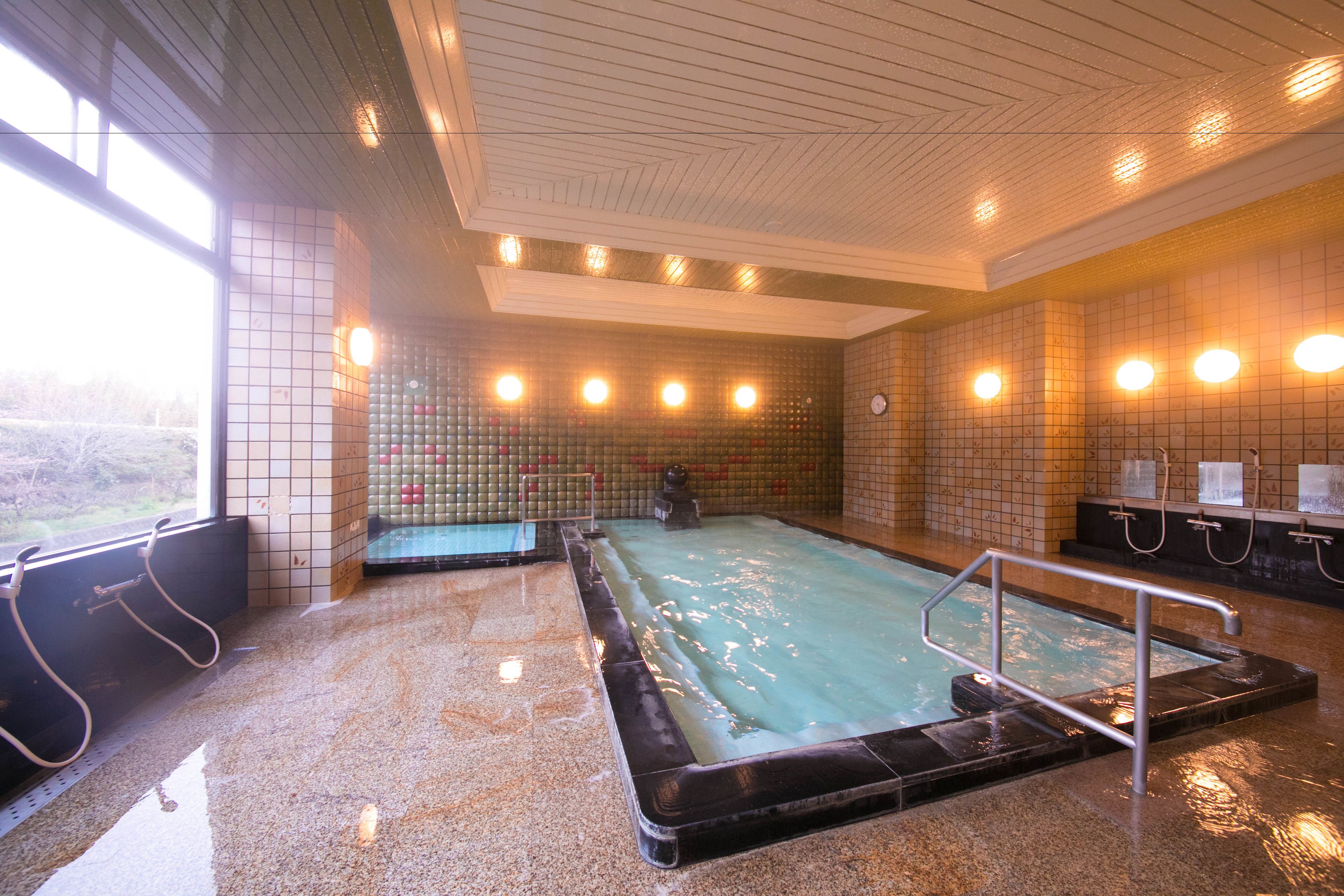 A large indoor swimming pool with a tiled wall and a metal railing.
