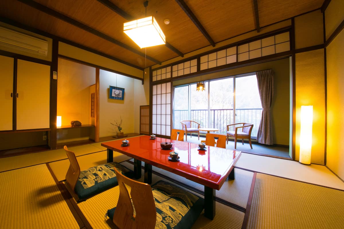 A traditional Japanese room with tatami flooring, a low table, and wooden chairs.