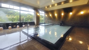 A large indoor swimming pool with a tiled wall and a window providing a view of greenery outside. - Seishounagon (Tsu)