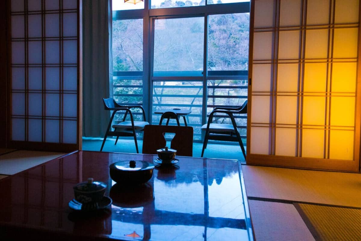 A traditional Japanese room with tatami flooring, a low table with a tea set, and sliding doors.