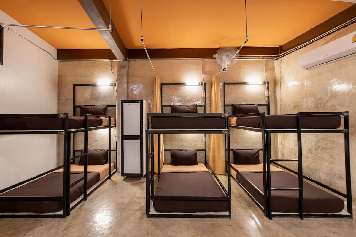 A bunk bed room with a central desk, a ceiling fan, and a wall-mounted air conditioner.