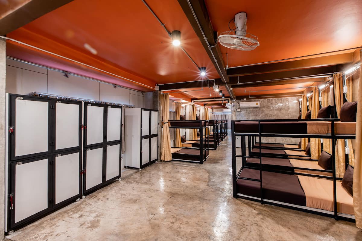 A hotel corridor with bunk beds, lockers, and a concrete floor.
