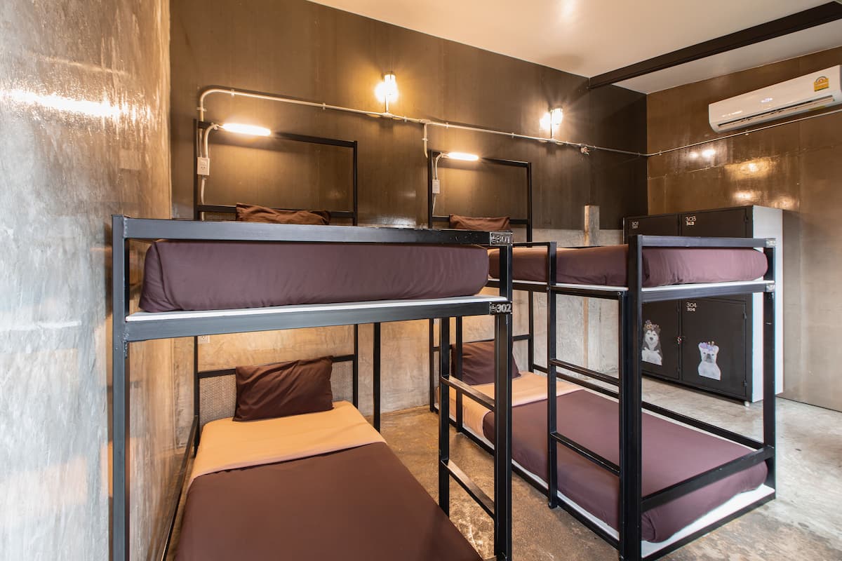 A bunk bed room with a wooden floor, metal bunk beds, and a small cabinet with a dog sticker.