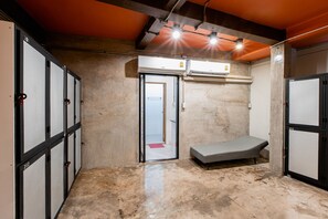 A room with a single bed, a door leading to another room, and a wall-mounted air conditioning unit. - The Alley Hostel & Bistro (Bangkok)