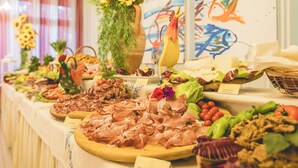 A buffet table with various food items and a decorative vase with sunflowers. - Hotel Stella del Mare (Cervia)