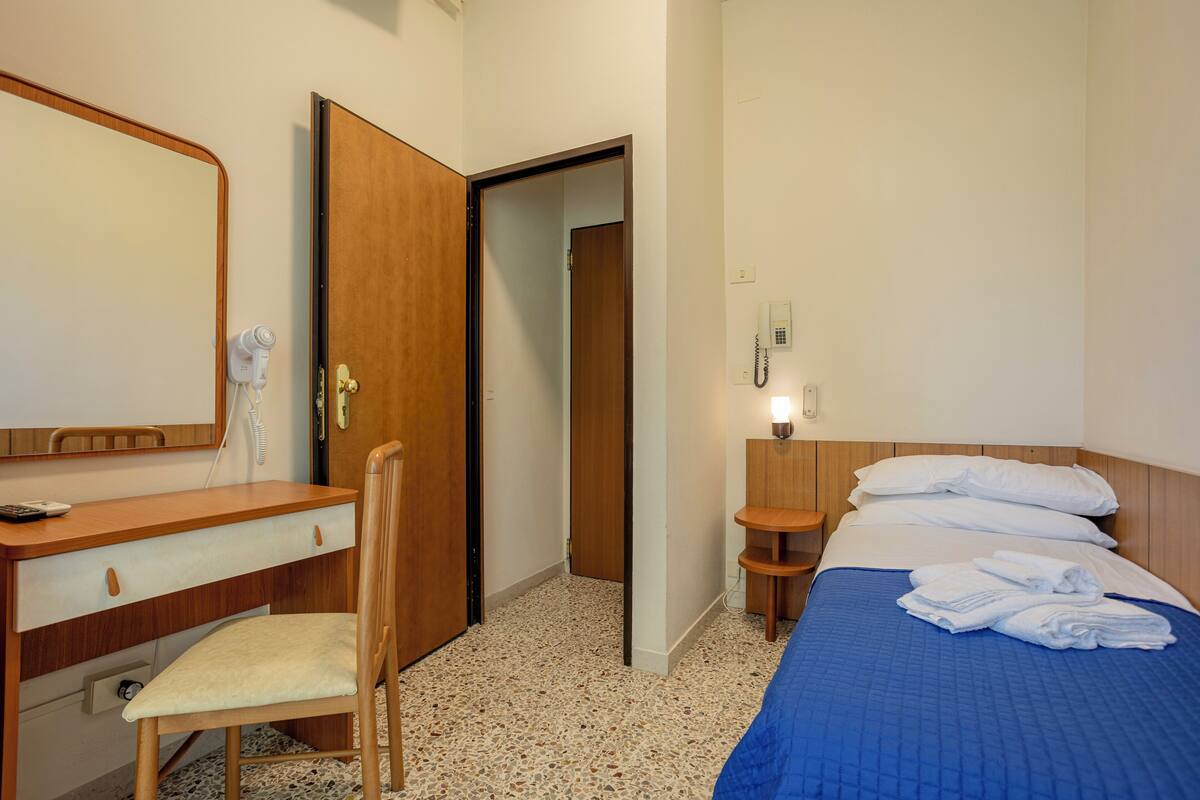 Una habitación de hotel con un escritorio de madera, una silla y una cama con ropa de cama azul.