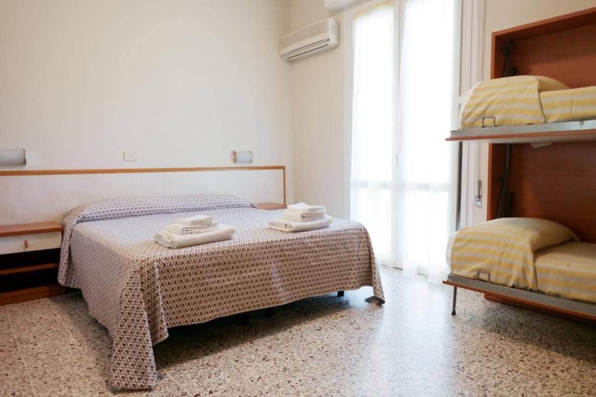 Una cama individual con una colcha estampada, una mesita de noche y una estantería empotrada con un cojín a rayas amarillas.