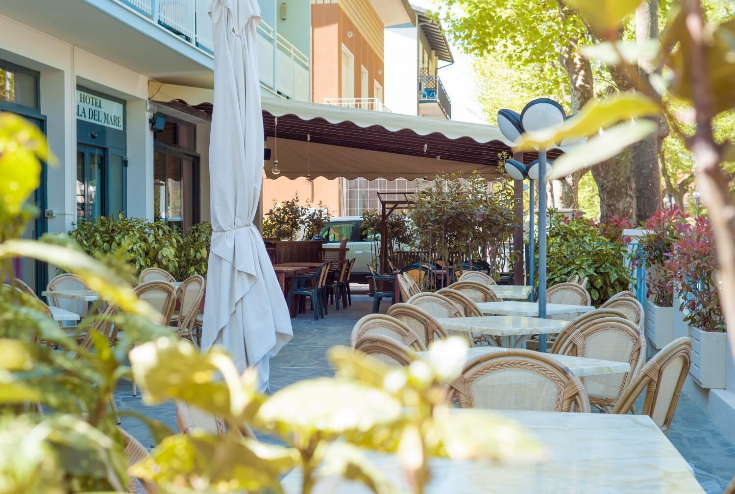 A hotel patio with outdoor seating, a covered area, and potted plants.