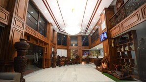 A spacious lobby with high ceilings, wooden paneling, a chandelier, and a large mirror reflecting the interior. - Le Mont Hotel (Phnom Penh)
