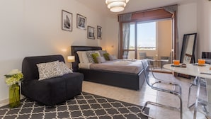 Un dormitorio moderno con cama, sofá, mesa de comedor y vistas al exterior.