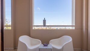 Una habitación con dos sillas blancas y una mesita con un tazón morado.