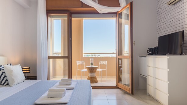 Una habitación de hotel moderna con cama, mesa de comedor, sillas y una zona de cocina.