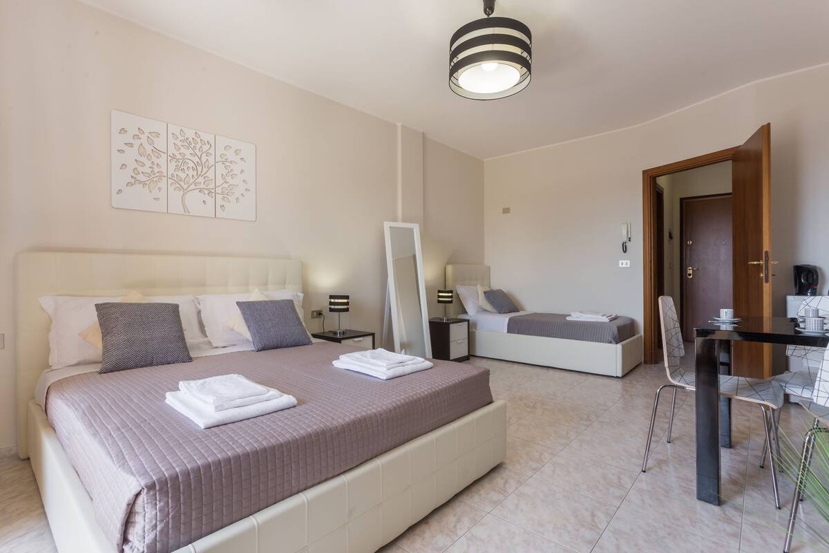 A modern hotel room with a large bed, bedside tables, a desk, and a chair.