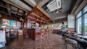 A bar area with wooden floors, bar stools, and a wooden counter with bottles. - Chengdu Sonderia Hostel&Bar-Lazybones (Chengdu)