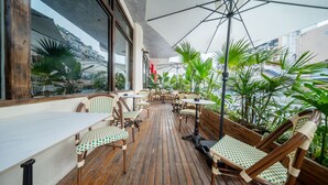 An outdoor patio with wooden flooring, wicker chairs, and tables. - Chengdu Sonderia Hostel&Bar-Lazybones (Chengdu)