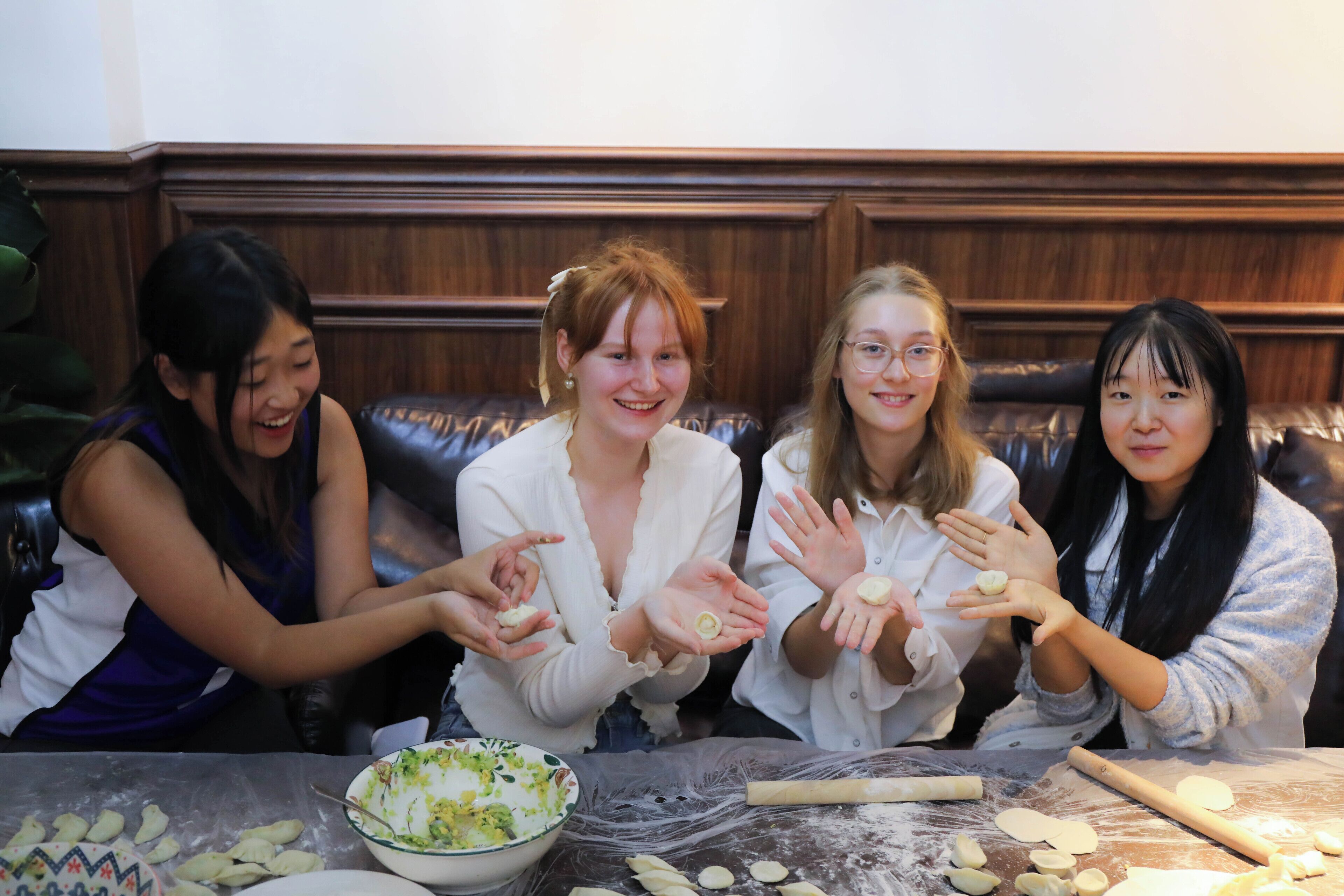 Four individuals seated at a table with dough and baking tools, suggesting a cooking or baking activity.