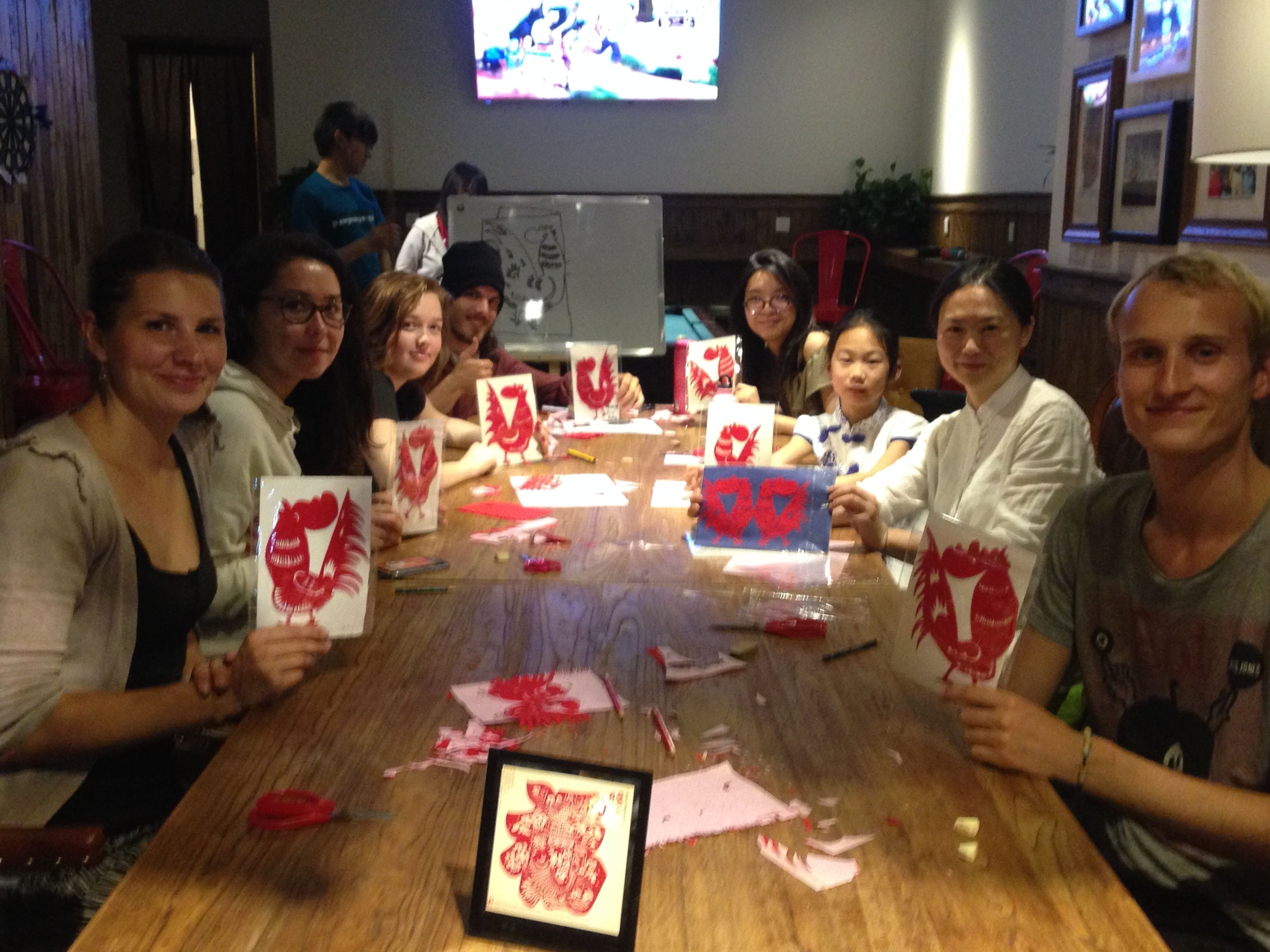A group of people sitting around a table with red artwork and papers.