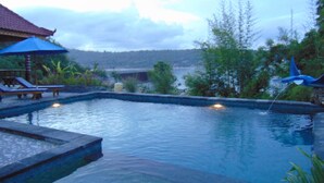 A swimming pool with lounge chairs and a blue umbrella. - Starfish Lembongan (Lembongan Island)