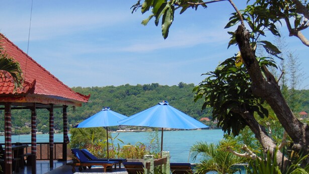 A beachside lounge with blue umbrellas, a tiled deck, and a view of the sea and greenery. - Starfish Lembongan (Lembongan Island)