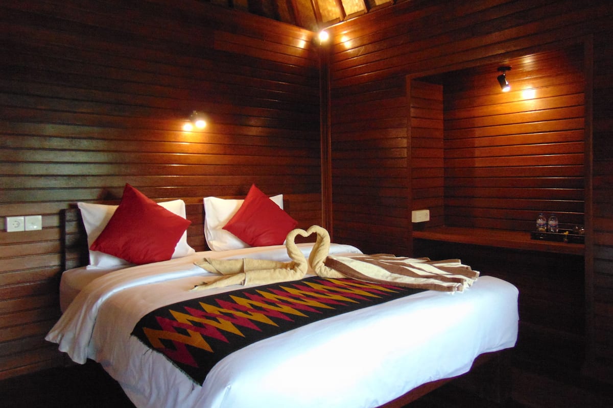 A wooden cabin-style room with a bed, pillows, and a blanket.