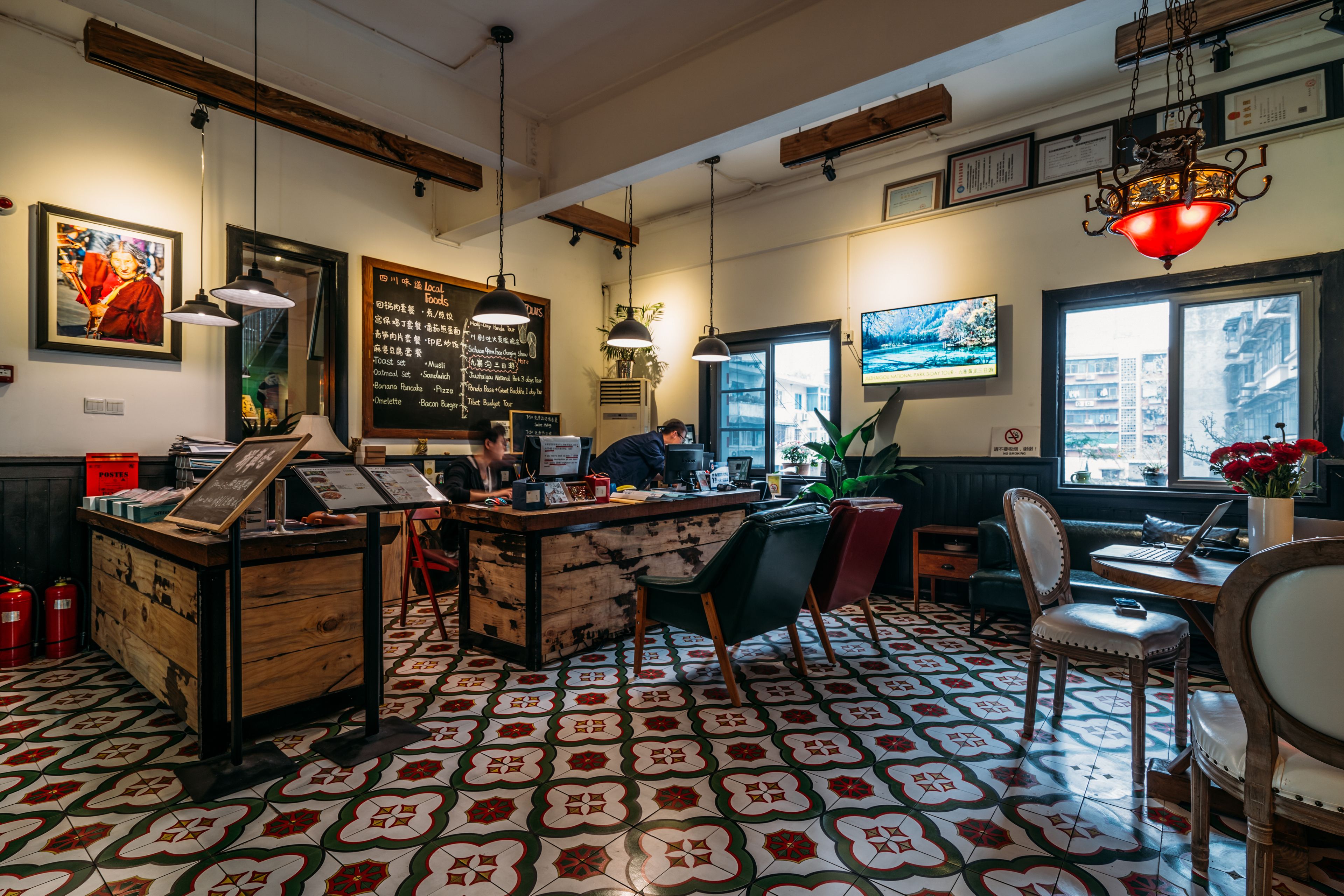 A restaurant interior with a wooden counter, tiled floor, and various seating options including chairs and a bench.