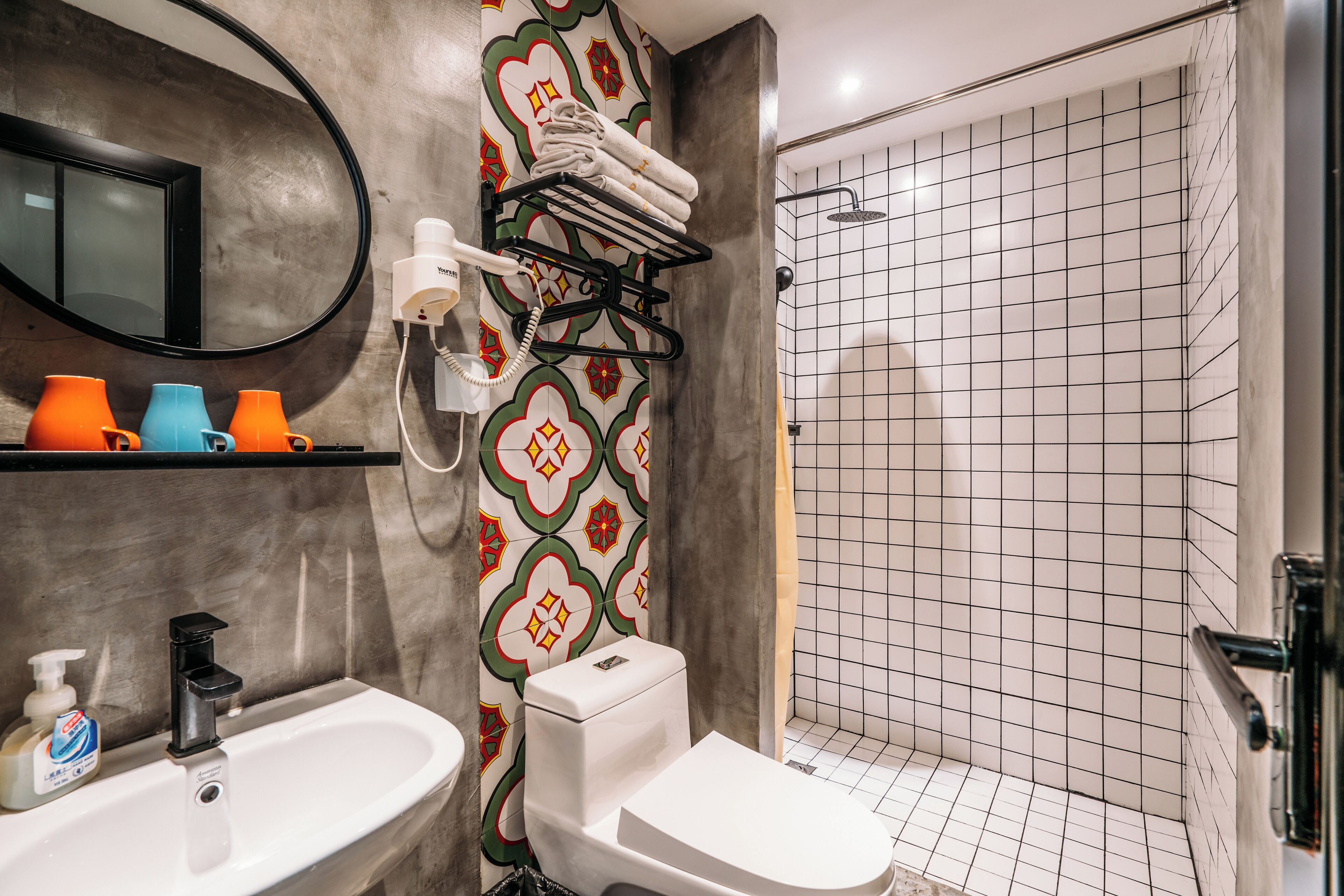 A bathroom with a sink, toilet, towel rack, and shower.