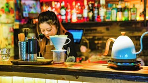 Un comptoir de bar avec une machine à café, une théière et une tasse.