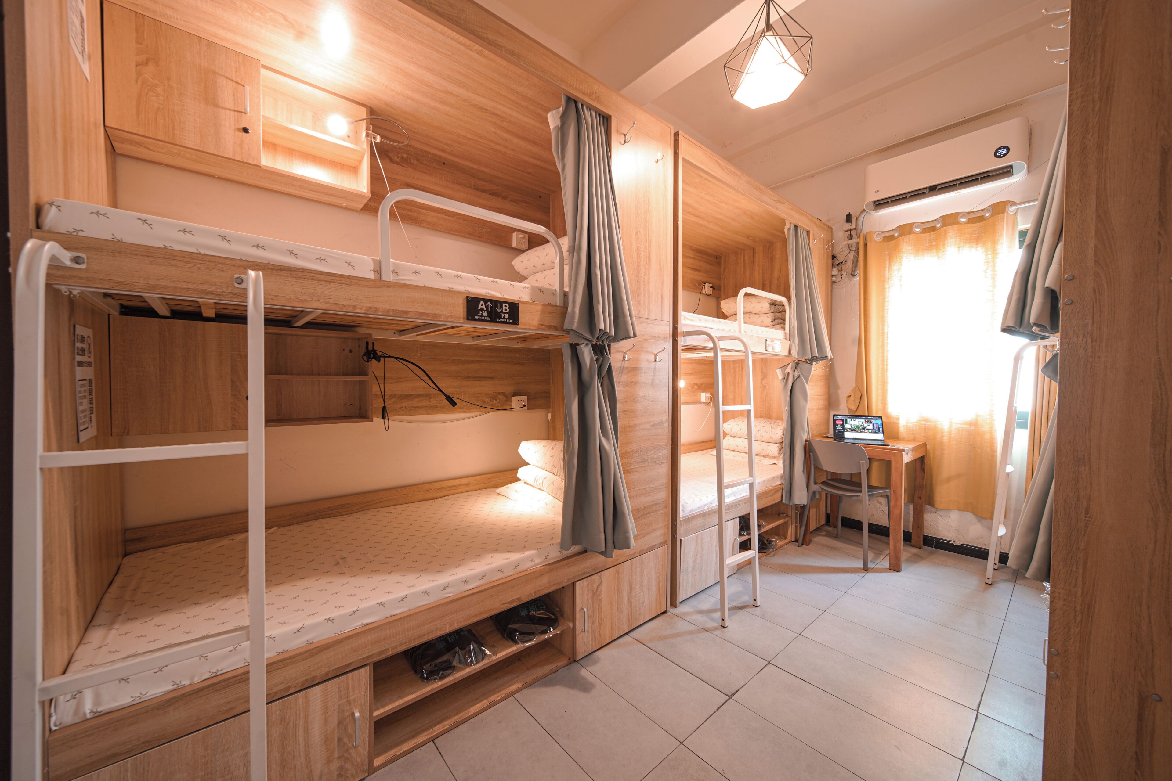 Dormitorio con literas, un escritorio, una silla, paredes de madera y un equipo de aire acondicionado.