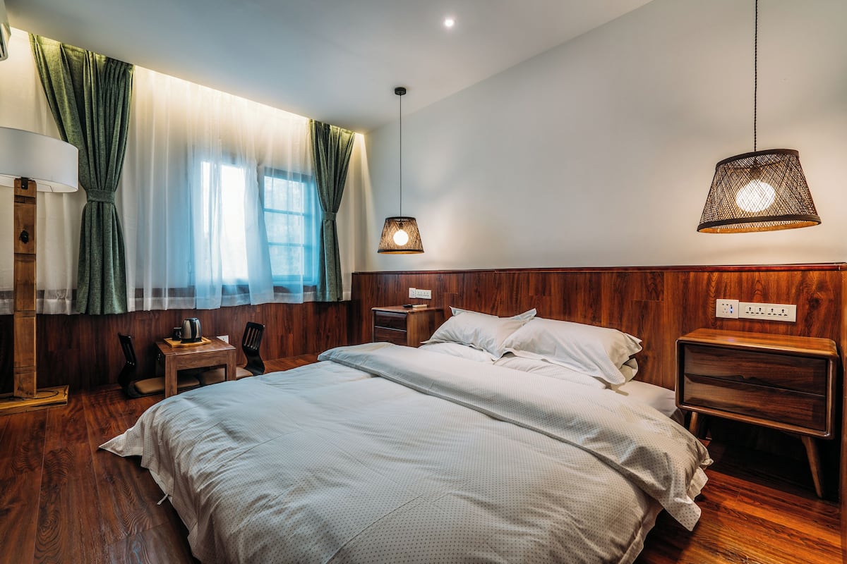 A neatly made bed with a wooden headboard, a bedside table with a lamp, and a nightstand with a lamp.