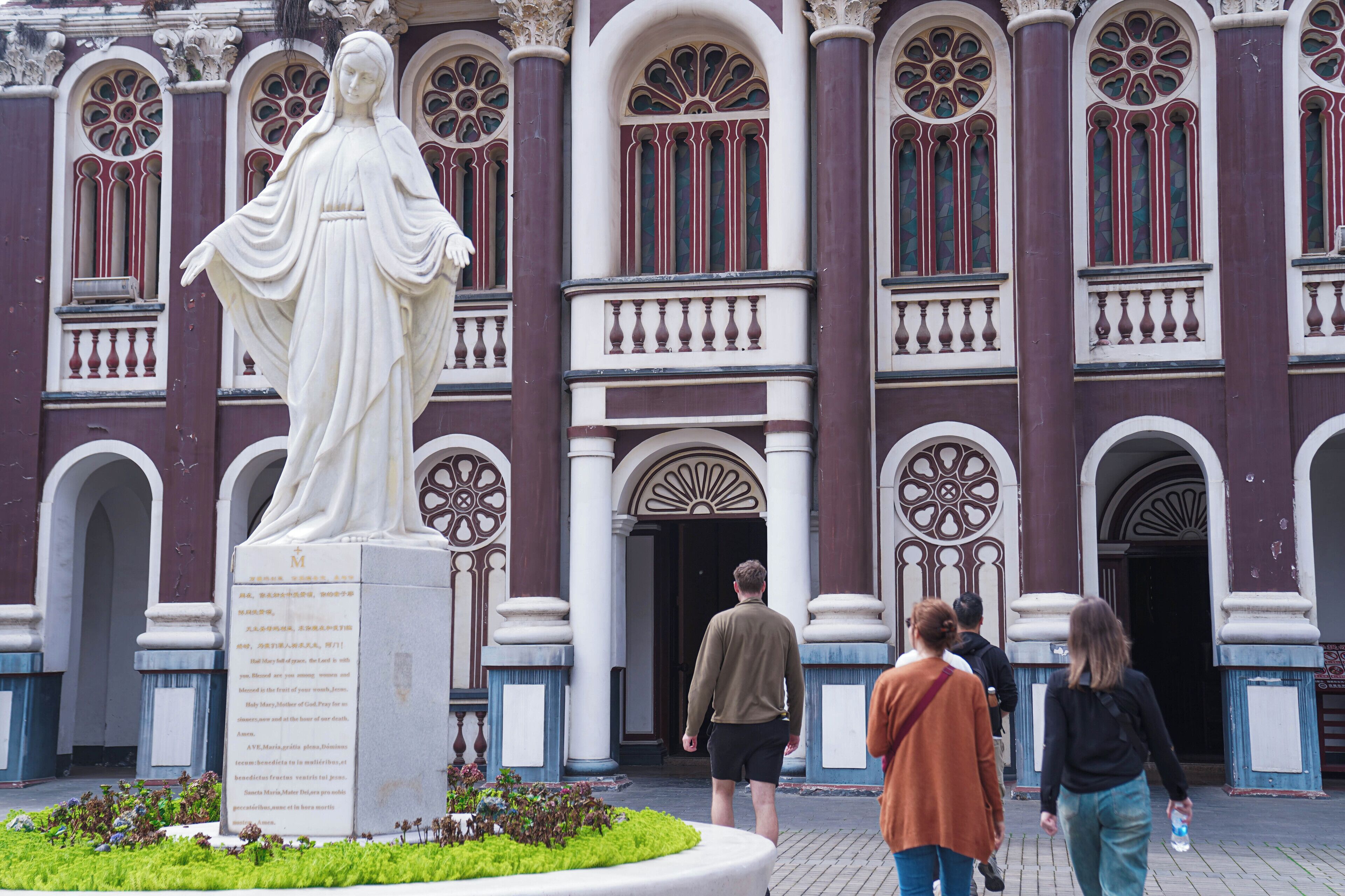 A statue in front of a building with arched windows and columns.