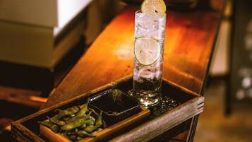 A tall glass with ice and lime slices on a wooden tray.