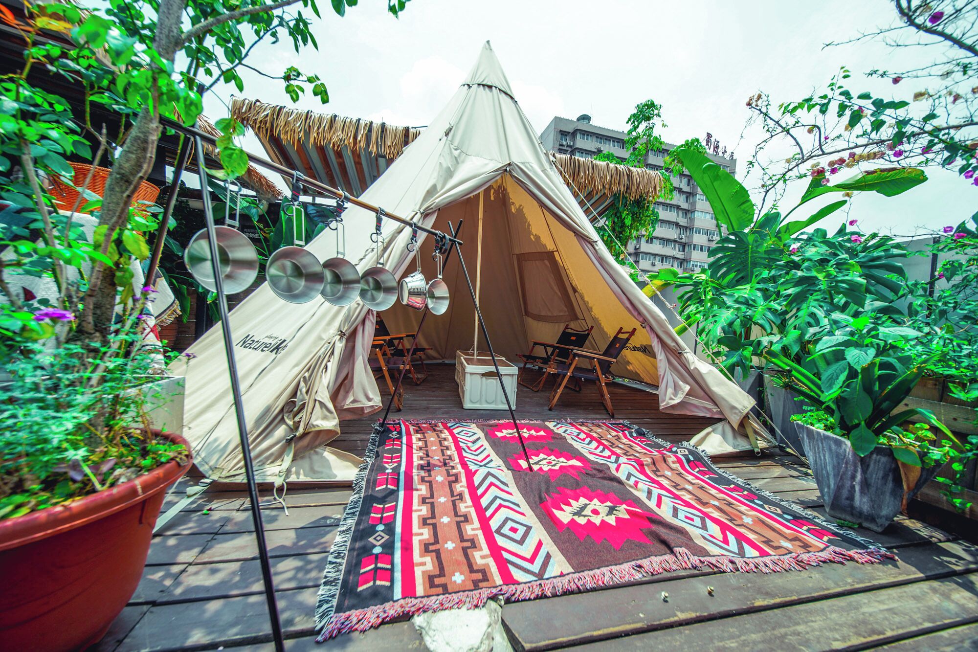 A tent with a mirrored ceiling, a patterned rug, and potted plants.