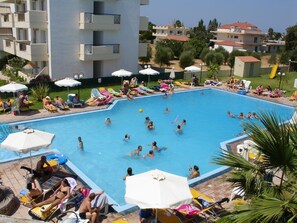 Una piscina al aire libre, sombrillas, sillones reclinables de piscina