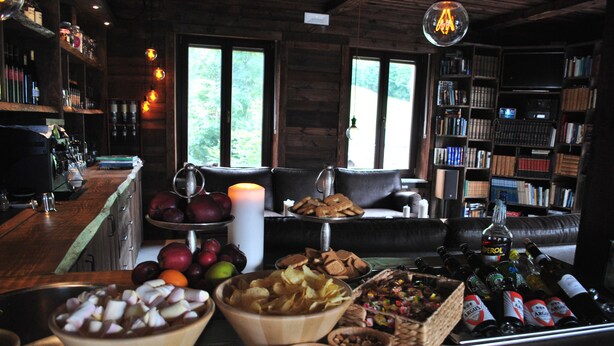 Una habitación acogedora con una zona de bar, un espacio de estar con un sofá y una estantería llena de libros.