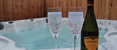 A hot tub with two champagne glasses and a bottle of Prosecco.