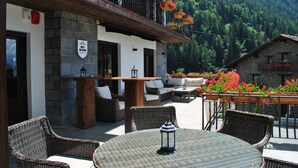 Un hotel con terraza al aire libre, paredes de piedra y jardineras con flores.