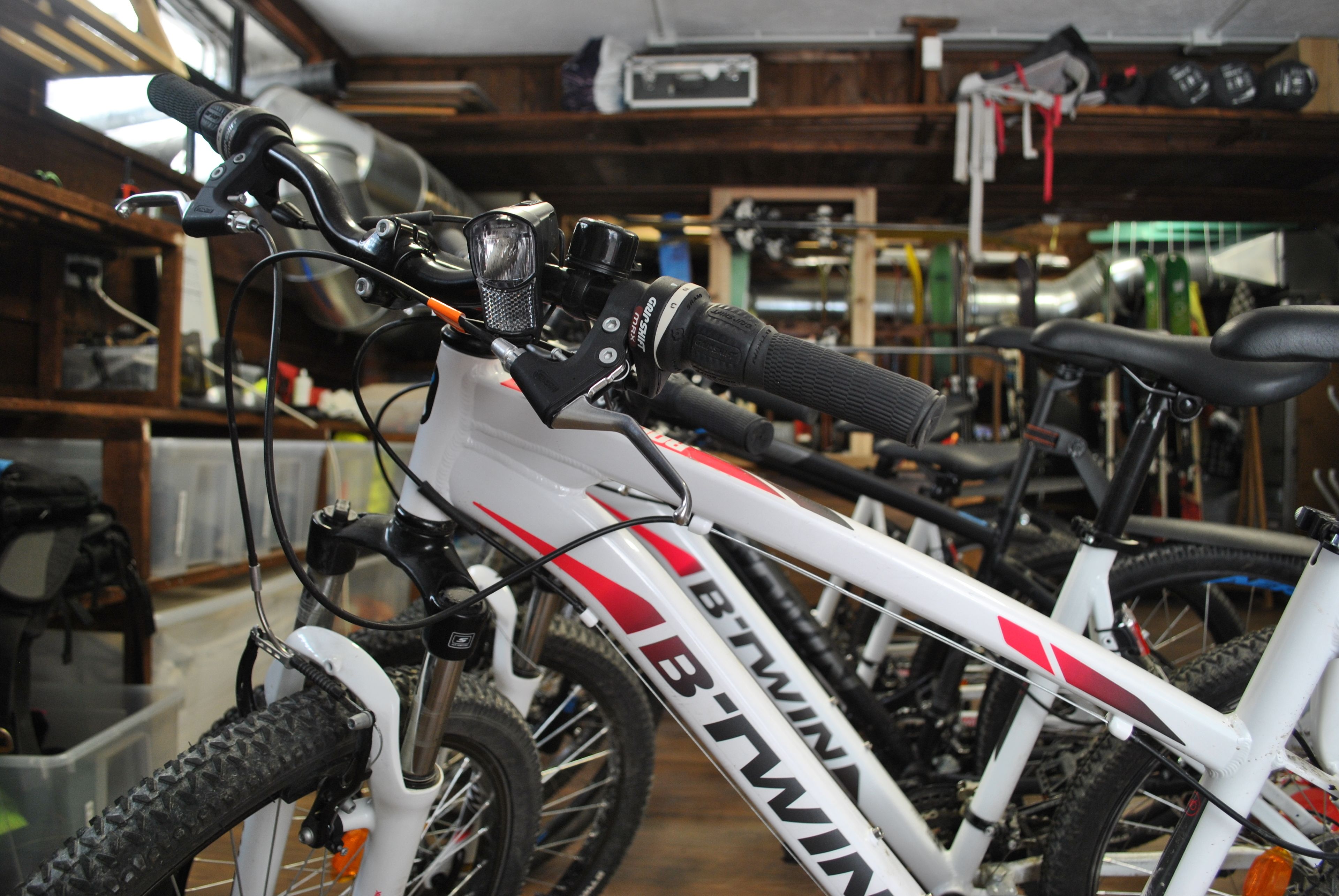 A white mountain bike with red accents and the brand name "B'TWIN" visible on the frame.