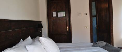 A bedroom with a wooden headboard, a bed with white bedding, and a door with a blue frame.